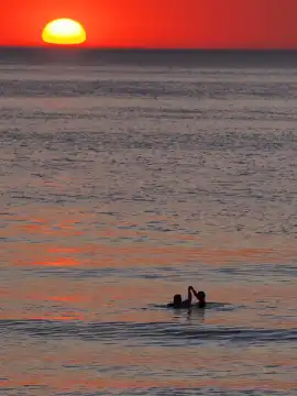 Couple in the sea at sunset