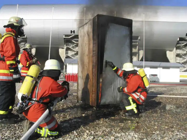 Feuerwehrmaenner mit Atemschutz bekaempfen einen Brand