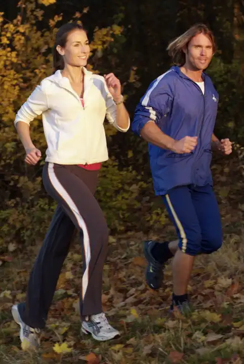 Woman and man jogging in autumn forest