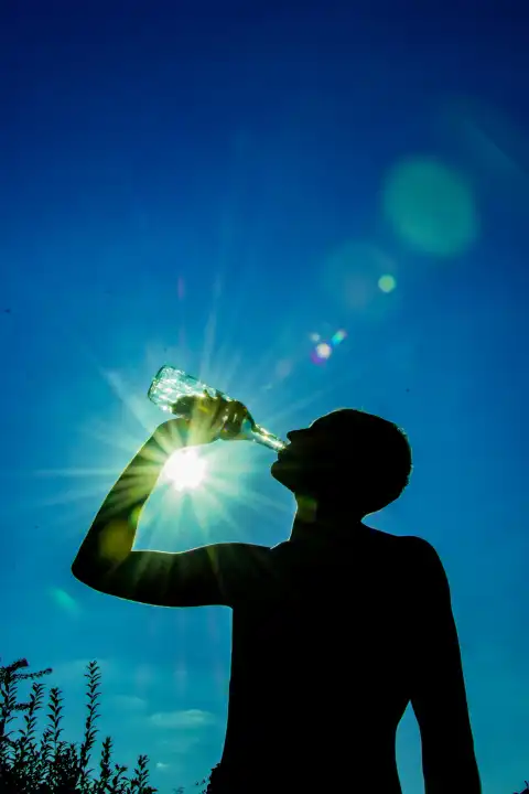 Mann trinkt Wasser in der strahlenden Sonne