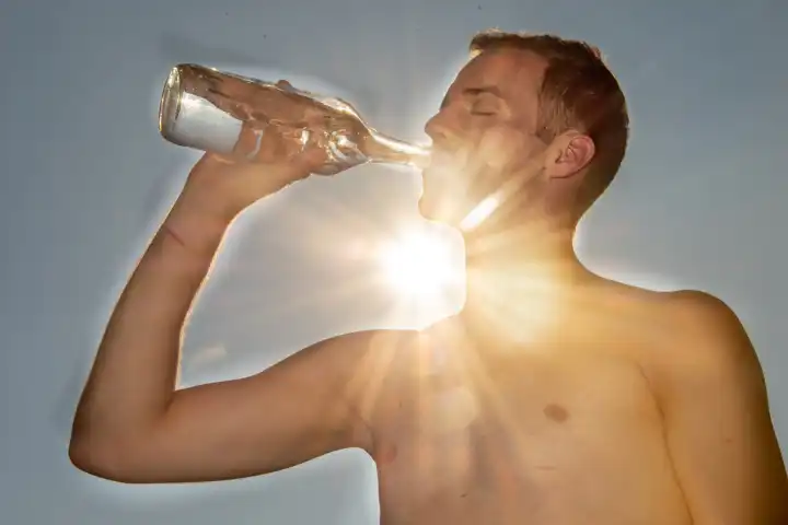 Young man drinks water in the heat of the sun