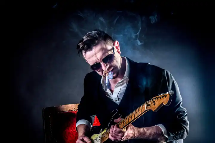 Cooler Musiker spielt auf einer Gitarre und raucht Zigarette