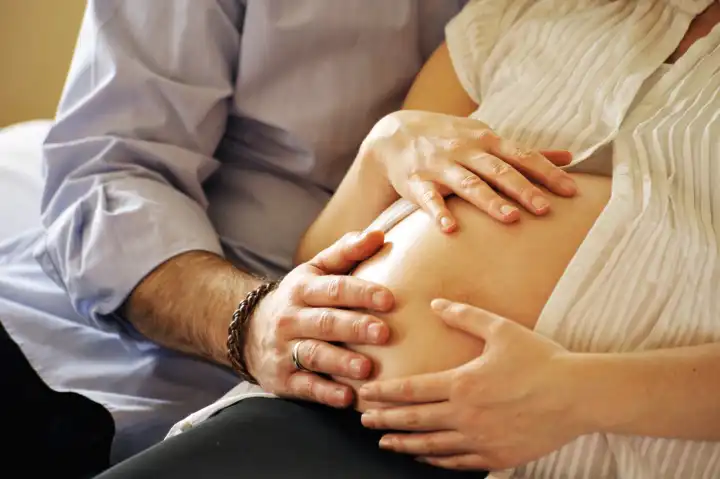 Hände eines Ehepaars auf schwangerem Bauch