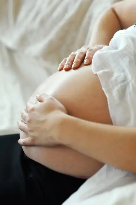 Woman, pregnant, hands on the belly