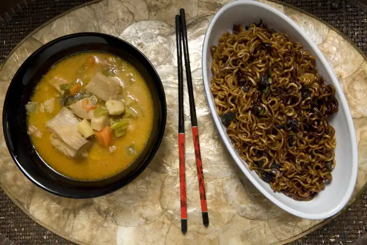 Asian vegetable fish soup and fried noodles in small bowls with chopsticks