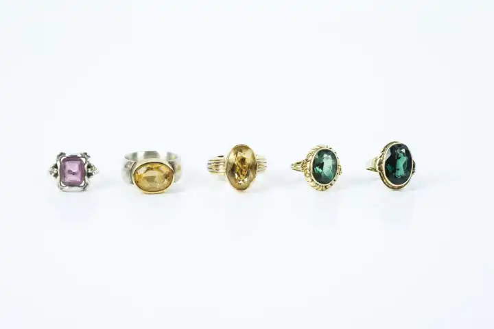 five rings with colorful stones in a row against white background