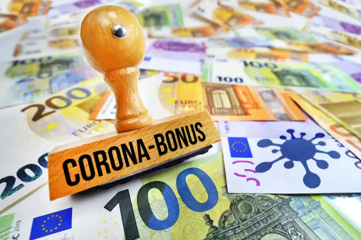 Stempel mit Aufschrift Corona-Bonus und Coronavirus-Symbol auf Geldscheinen