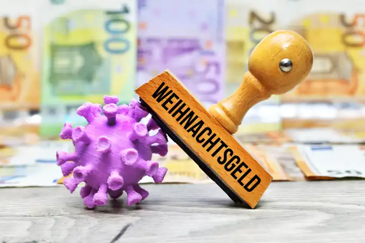 Stempel mit Aufschrift Weihnachtsgeld und Coronavirus-Modell vor Geldscheinen
