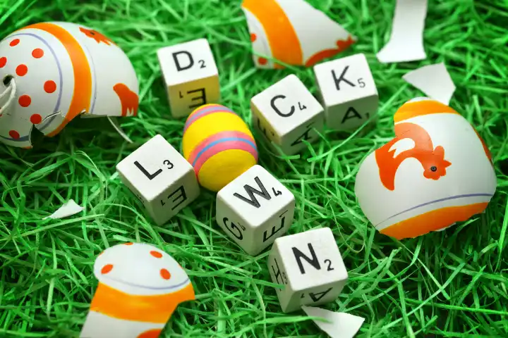 Buchstaben formen das Wort Lockdown in einem Osternest mit zerbrochenem Osterei, Symbolfoto harter Lockdown zu Ostern