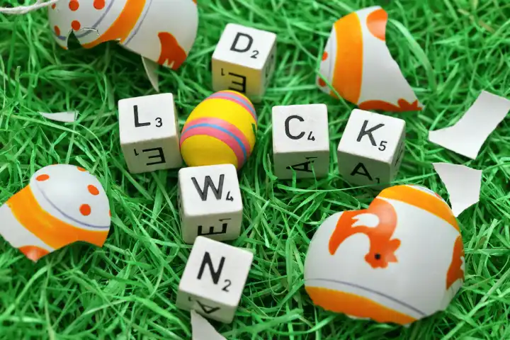 Buchstaben formen das Wort Lockdown in einem Osternest mit zerbrochenem Osterei, Symbolfoto Oster-Lockdown
