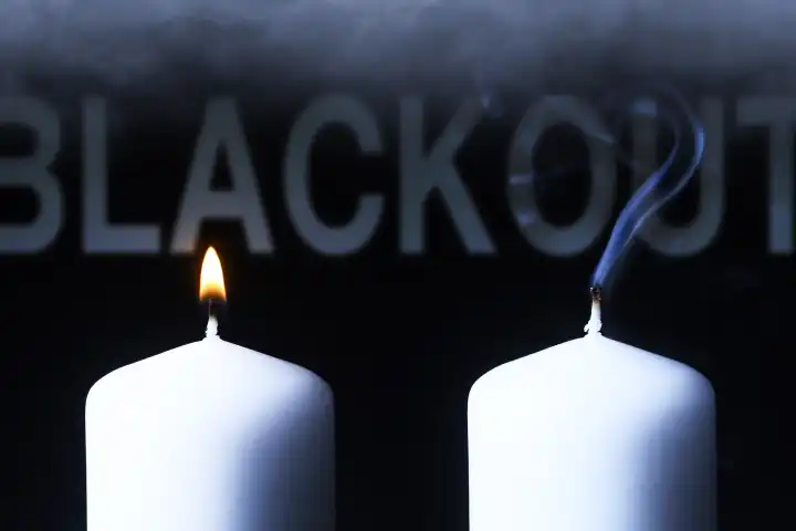 Brennende und ausgelöschte Kerze mit Schriftzug Blackout