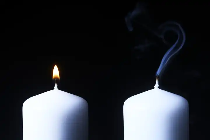 Burning and extinguished candle, symbol photo blackout
