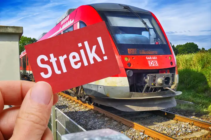 Hand holding sign with inscription strike in front of a train, symbol photo train strike