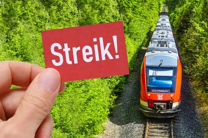 Hand hält Schild mit Aufschrift Streik vor einer Bahn, Symbolfoto Bahnstreik