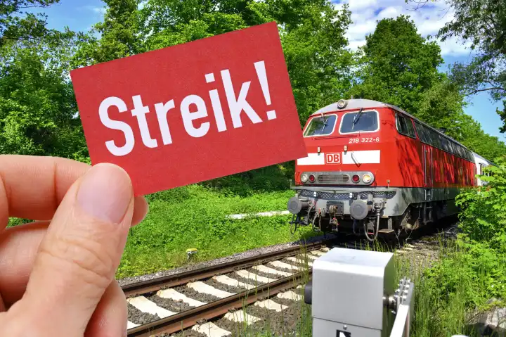 Hand holding sign with inscription strike in front of a train, symbol photo train strike