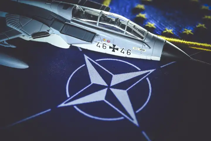 Military jet model on NATO flag, symbol photo Air Defender 2023 NATO air maneuver