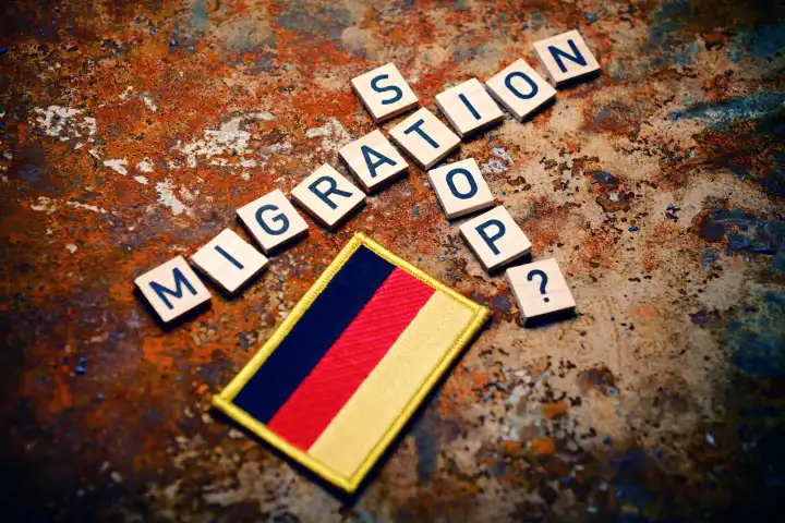 Schriftzüge Migration und Stop mit Fragezeichen neben Fahne von Deutschland, Symbolfoto Migrationskrise