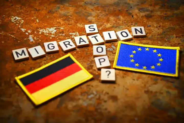 Schriftzüge Migration und Stop mit Fragezeichen neben EU- und Deutschland-Fahne, Symbolfoto Migrationskrise