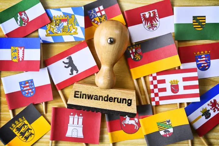 Stempel mit Aufschrift Einwanderung inmitten Fahnen der deutschen Bundesländer