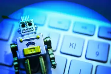 Roboterfigur liegt auf einer Computertastatur, Symbolfoto künstliche Intelligenz, Fotomontage