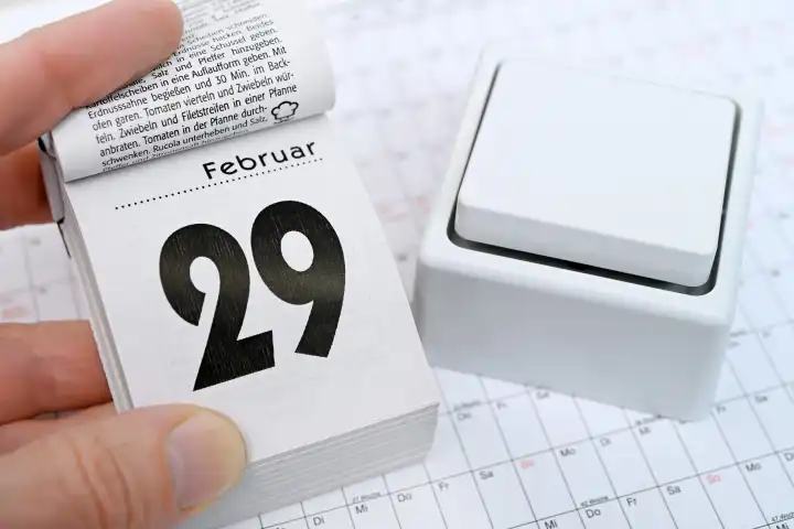Hand mit Kalenderblatt vom 29. Februar und Schalter, Symbolfoto Schaltjahr