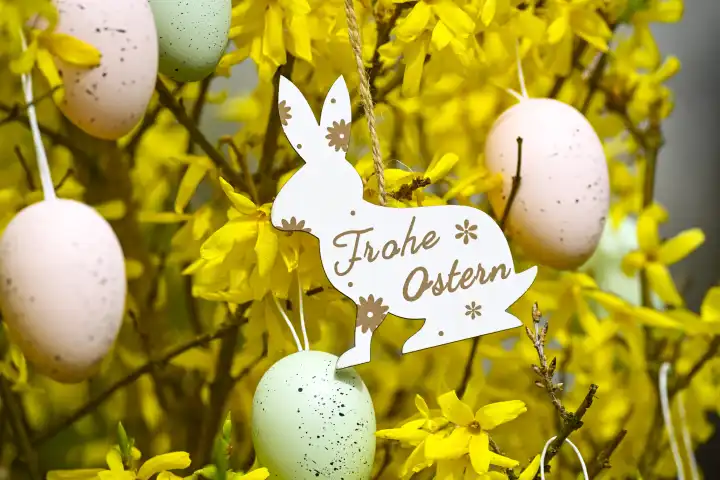 Easter bunny pendant with the inscription Happy Easter on a forsythia bush with Easter eggs