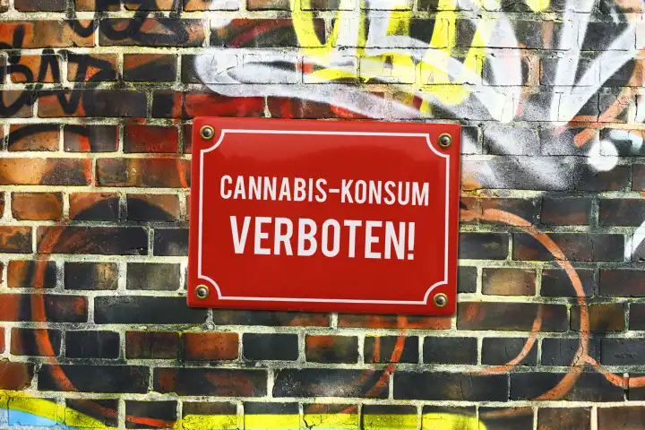 Schild mit Aufschrift Cannabis-Konsum verboten! an einer Mauer, Fotomontage