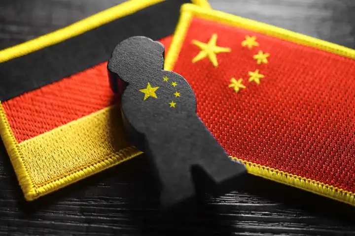 Black figure on the flags of Germany and China, symbolic photo of Chinese espionage, photomontage