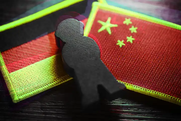 Schwarze Figur auf den Fahnen von Deutschland und China, Symbolfoto chinesische Spionage