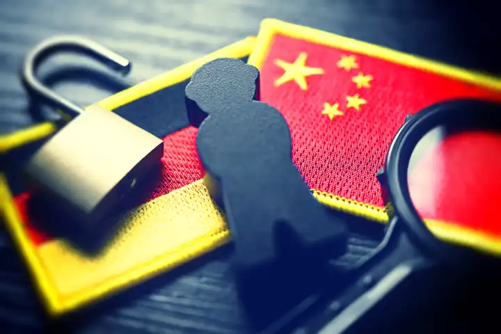 Schwarze Figur auf den Fahnen von Deutschland und China, Symbolfoto chinesische Spionage
