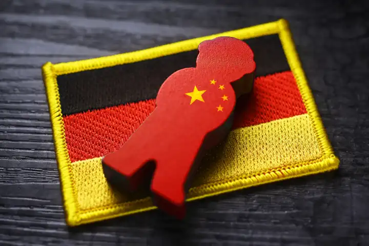 Spion-Figur mit China-Fahne auf der Fahne von Deutschland, Symbolfoto chinesische Spionage, Fotomontage