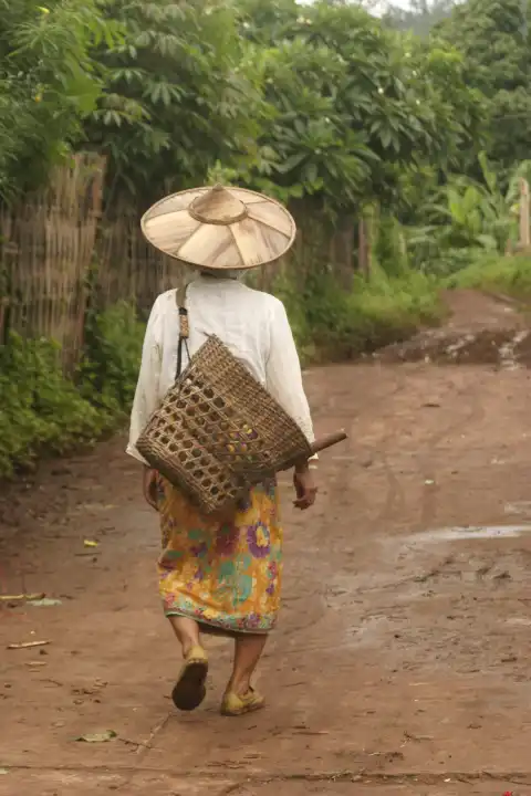 Asiatische Frau mit Hut geht Weg entland