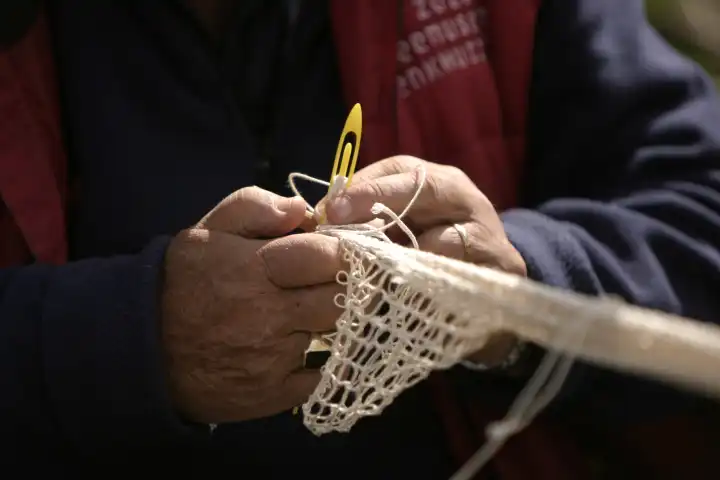 Hände beim Fischernetze reparieren
