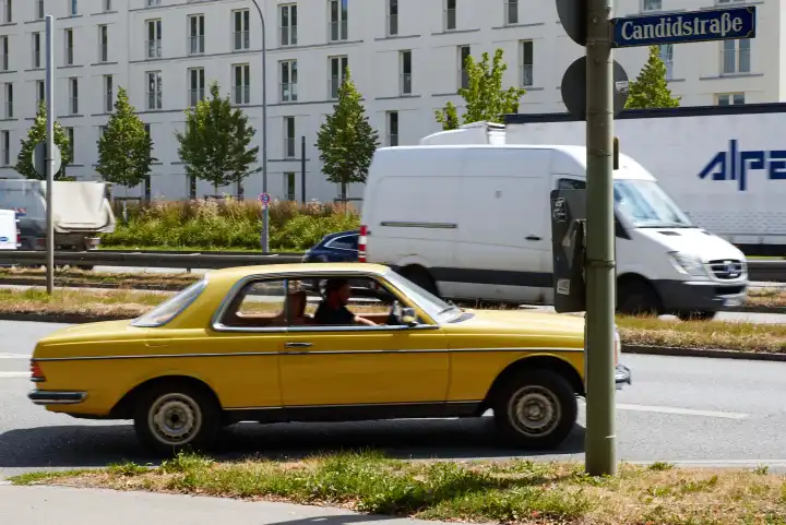 Yellow Mercedes BJ 1980s enters Candid street, street sign visible