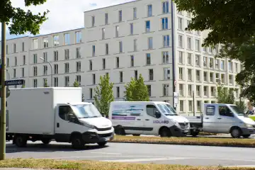 Verkehr mittlerer Ring / Candidstraße. Drei versetzt fahrende weiße Kastenwagen, Straßenschild sichtbar. Im Hintergrund Neubauwohnblock.