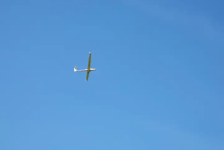 Glider with visible plastic rope from takeoff with blue sky.