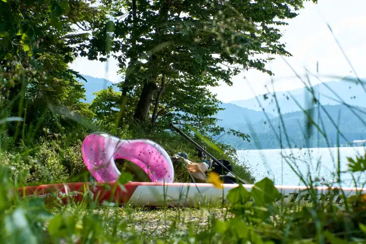 Walchensee. Bathing spot with pink heart, SUP board, beer bottles, bathing utensils. View of west shore and mountains.