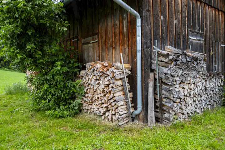 Bildhafte Umsetzung des geflügelten Wortes "Holz vor der Hütte haben" am Beispiel einer Hütte mit vorgelagertem Brennholz bei Maierhöfen im Westallgäu, Bayern, Deutschland.