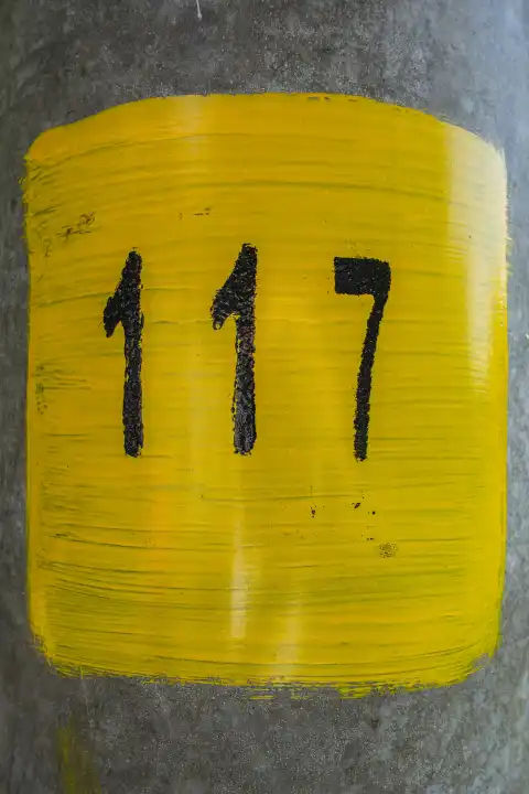 Number 117, one hundred and seventeen, painted black on yellow on a mast.
