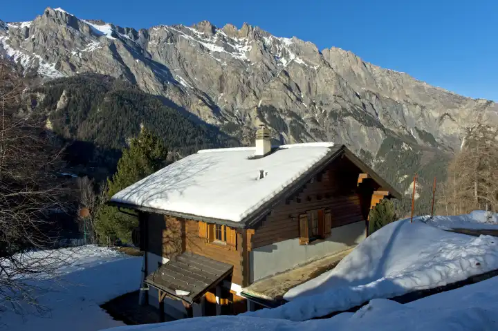Snow covered chalet in front of a rock face of the Swiss Alps, Mayens de Chamoson, Valais, Switzerland