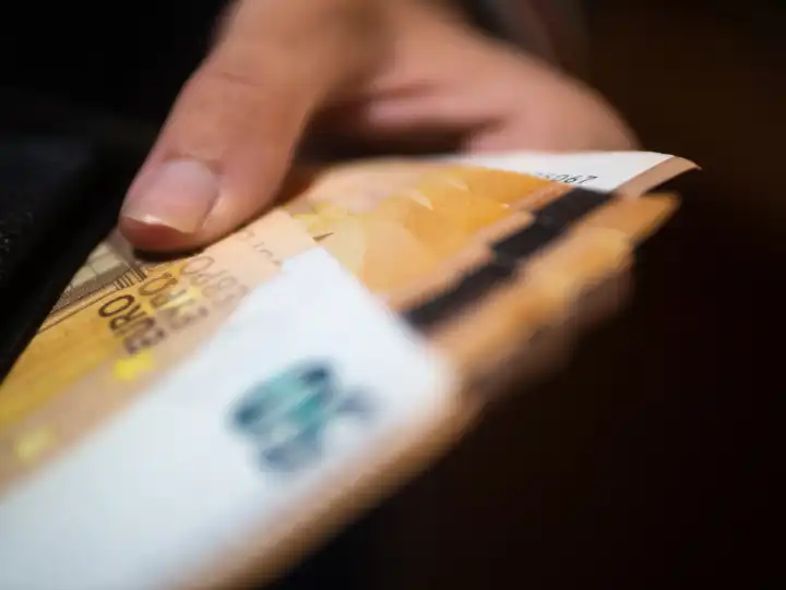 Person zieht Geldscheine aus einer Geldbörse / Portemonnaie