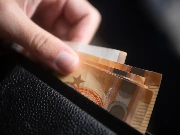 Person zieht Geldscheine aus einer Geldbörse / Portemonnaie