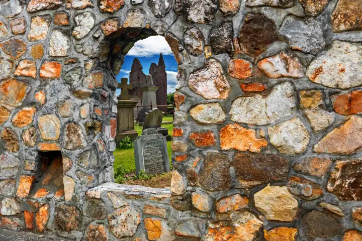 Blick durch ein Fenster einer historischen Mauer auf einen Friedhof in Schottland