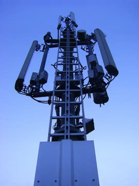 Mobilfunkmast vor blauem Himmel von unten nach oben fotografiert in blautönen