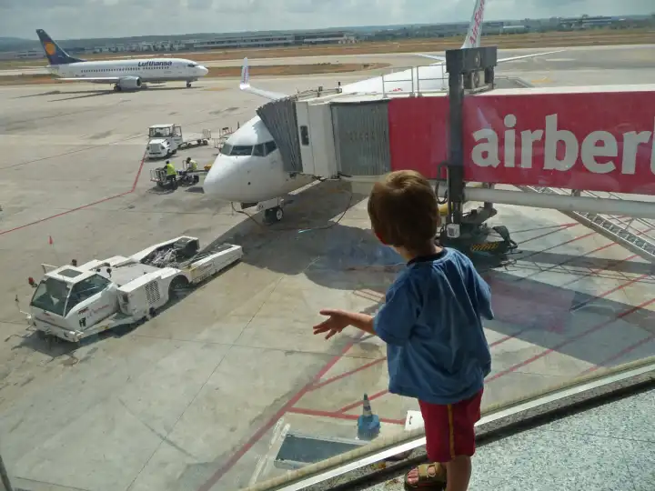 Little Boy is watching airplanes through a window of an AirPort
