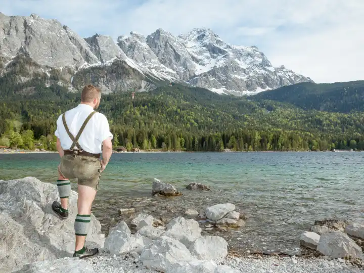 A traditional bavarian man at lake Eibsee with the Zugspitze mountain in the background