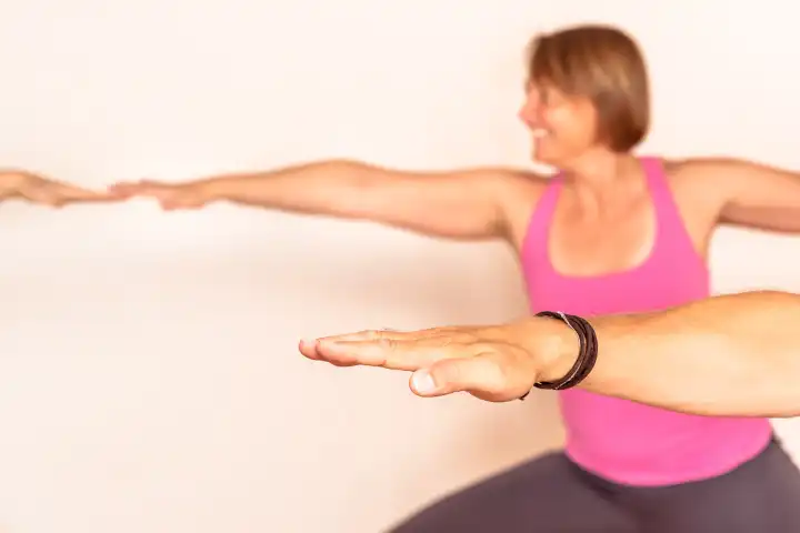 People doing yoga exercises. Hand in focus and woman blurred in the background.