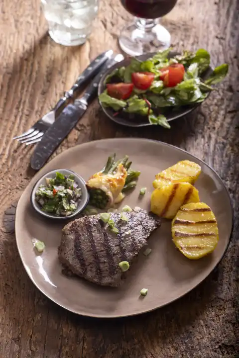Grilled steak with chimichuri sauce on wood 