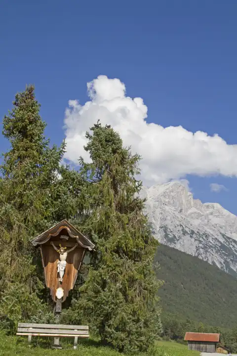 Idyllisches Wegkreuz mit Rastbank vor dem Gipfel der Hohen Munde In Tirol
