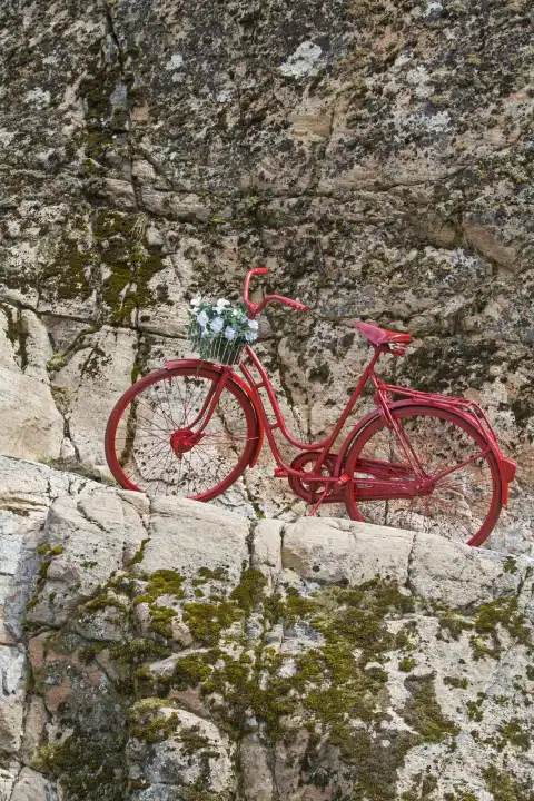 Decoratively placed red women s bike in a Norwegian rock face